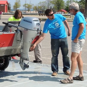 Volunteer emptying drain plug on boat