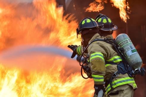 Two firefighters putting out a fire with a firehose.