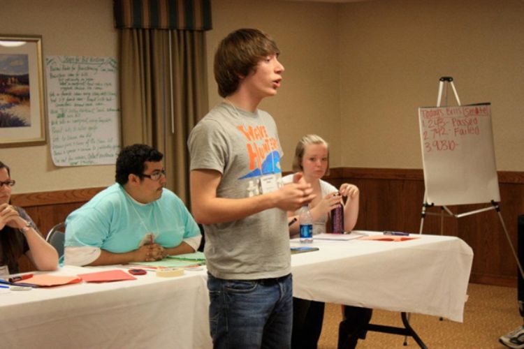 Young adult standing in front of group demonstrating public speaking skills during 4-H Capitol Experience.