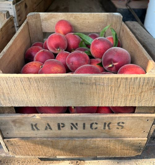 A wooden crate filled with peaches.