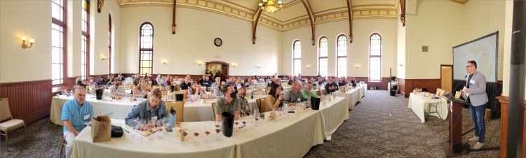 Participants sitting in a large conference room listening to someone speak at the front of the room.