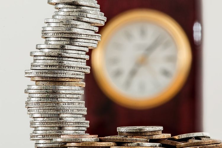 Coins stacked in front of a clock