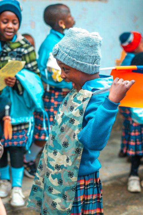 A child holding up their brand new dress with a huge smile on their face.