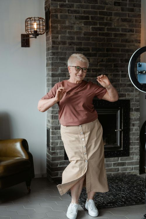 A photo of an older adult with glasses dancing in front of a phone.