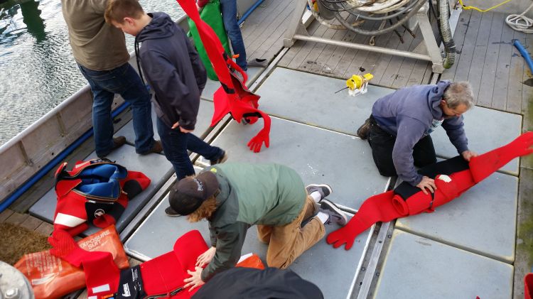 Alaska commercial fishermen on a purse seine vessel get immersion suits ready for use. Photo: Ron Kinnunen | Michigan Sea Grant