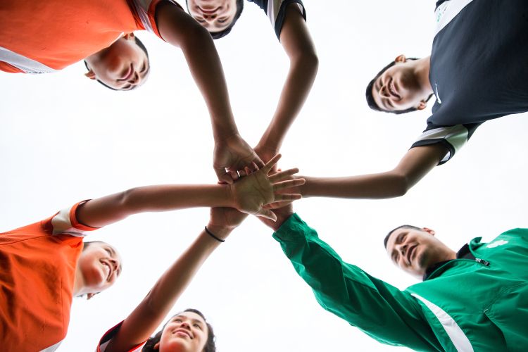 People with their hands together in a cheer.