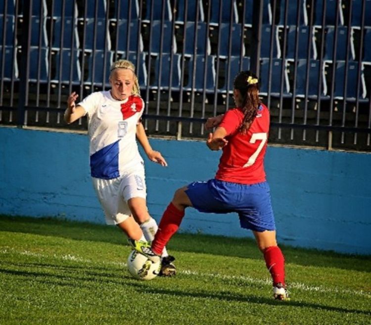 Two girls battling over the ball in soccer.