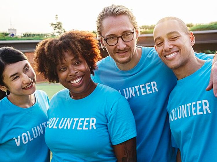 A group of diverse people in blue shirts that say volunteer.