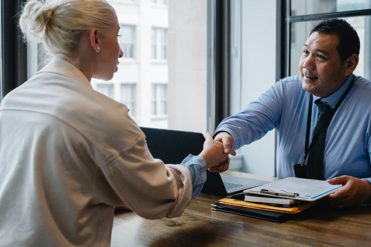 Two individuals in a business meeting shaking hands.