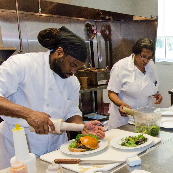 Two chefs prepare food to serve at a restaurant.