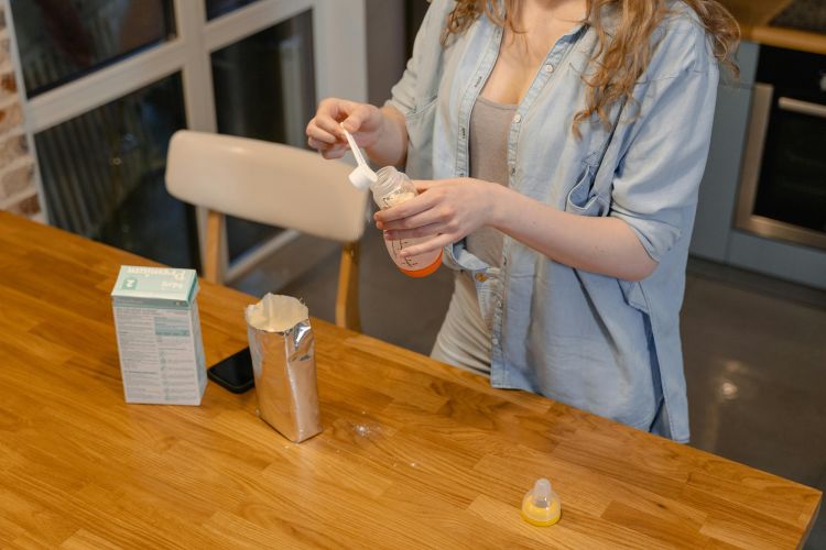 A photo of a woman safely preparing powdered infant formula.