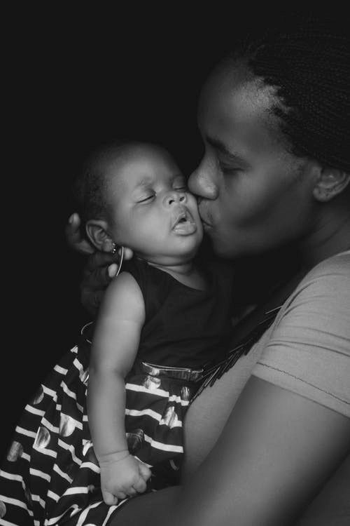 A mom kissing a baby.