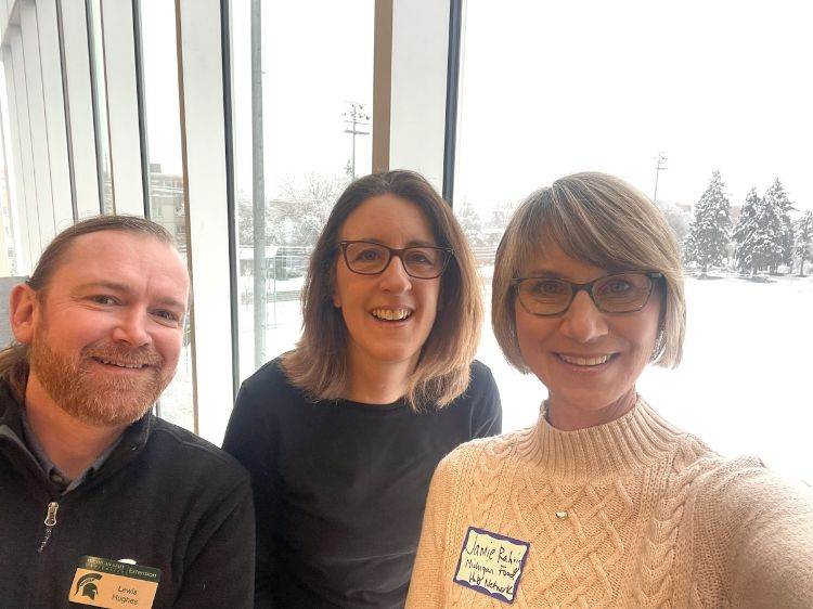 Lewis Hughes, Jude Barry, and Jamie Rahrig pose for a photo in front of the window, showing fresh snow in the background.