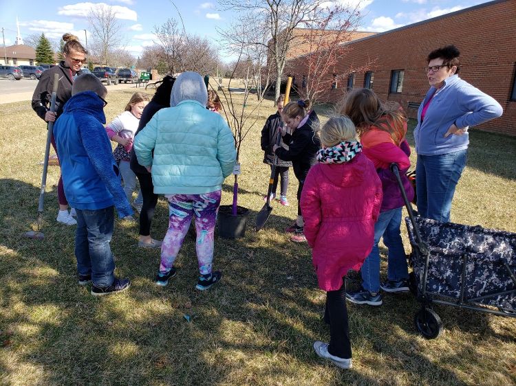 Adults and children planting a tree