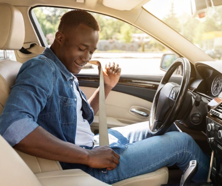 A person putting on their seat belt in a car.