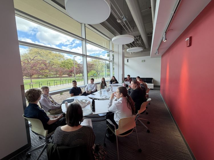 A group of young adults sitting around a table discussing.