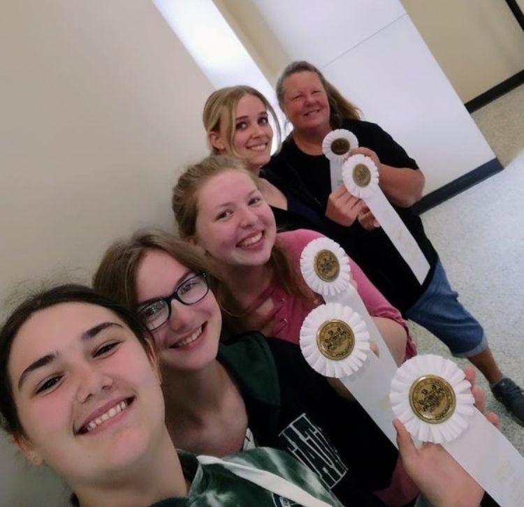 Four youth and their couch holding up the third place ribbons they earned.