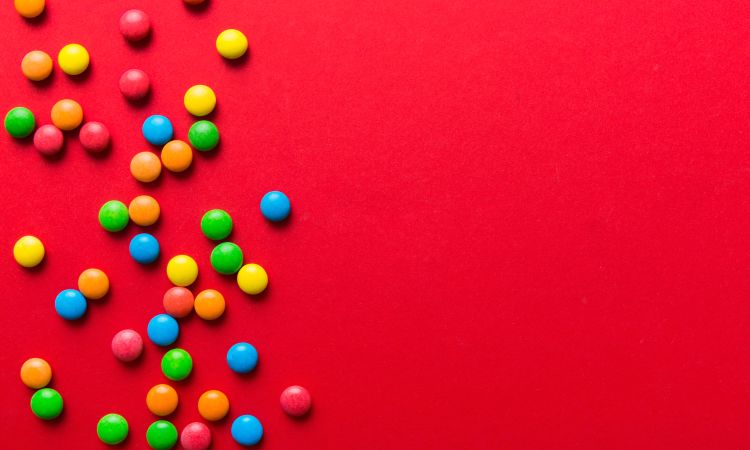 Small multi color candies on red background.