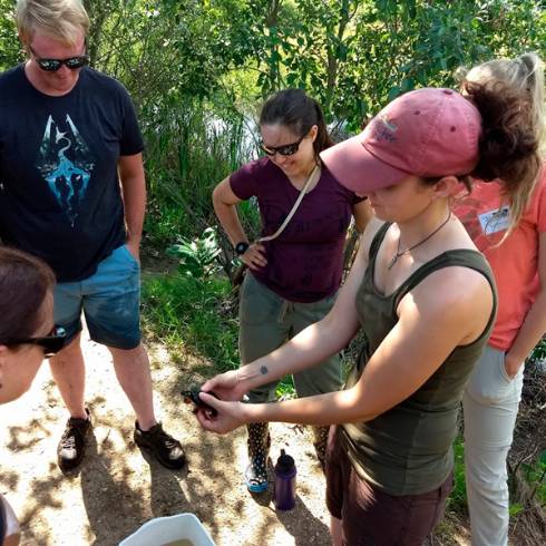 person holding turtle showing other people in a Michigan pond