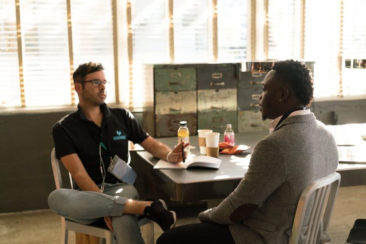 Two men talking with one another at a table.