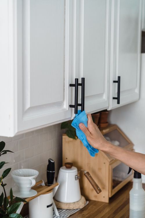 Someone wiping a kitchen cabinet.