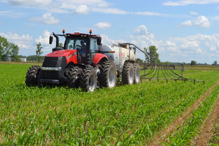 A red tractor spreading manure on a field.