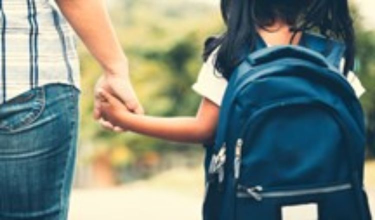 An adult holding the hand of a child.