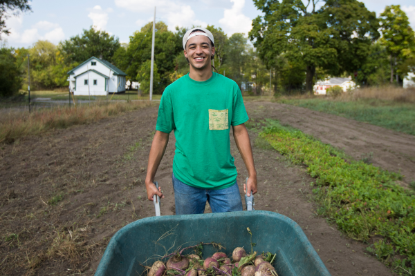 Young man pushing a wheelbarrow on an urban farm.