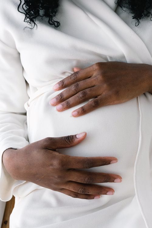 A person putting their hands on their pregnant stomach.