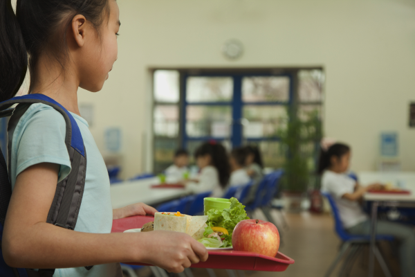 Young girl carries tray of food in cafeteria