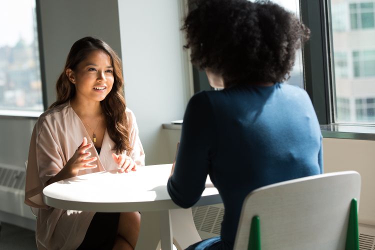 Two women sit at a table across from each other