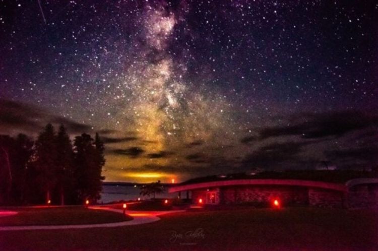A building dimly lit below a starry sky.