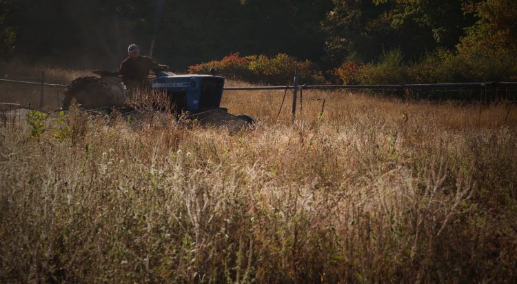 A farmer on a tractor driving through a field.