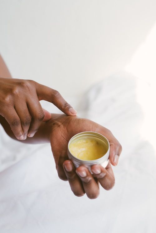 A pair of hands applying and holding a bottle of lotion