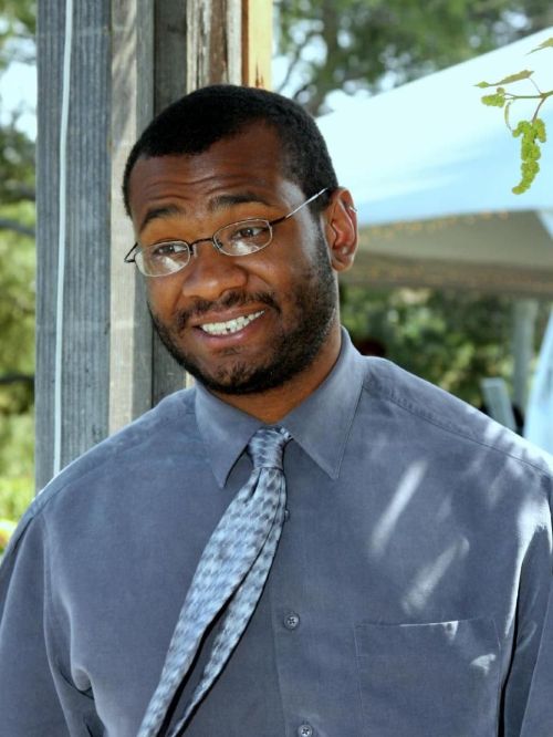 Dr. M. Jahi Chappell wearing a gray blue dress shirt and light blue tie.