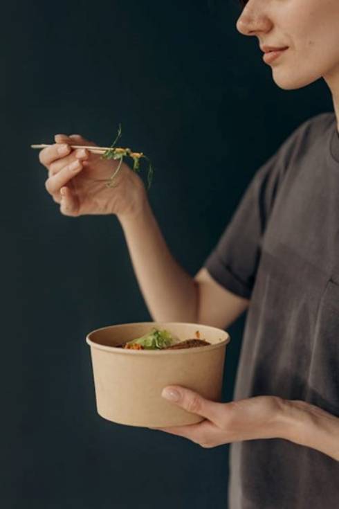 Woman eating from a bowl with chopsticks