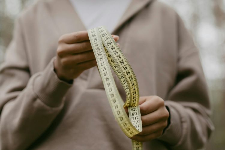 A person's hands holding clothes measuring tape.