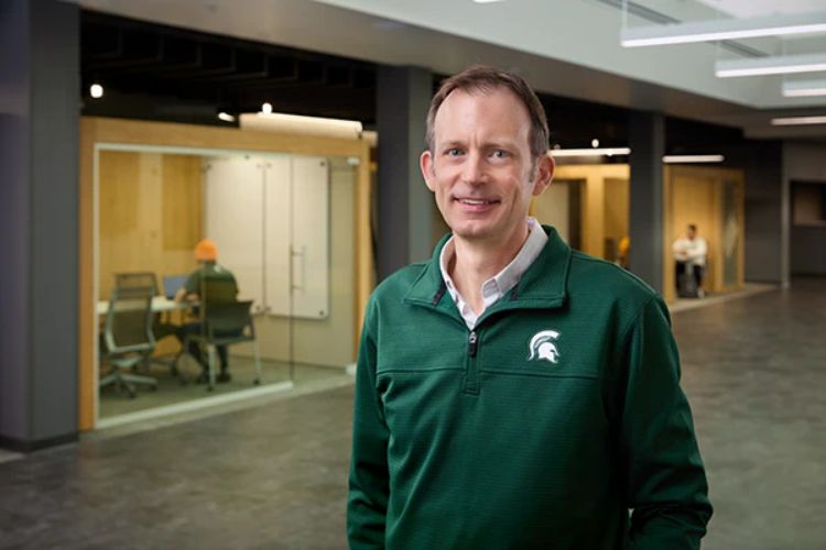 Matthew Daum smiling, wearing a green MSU pullover