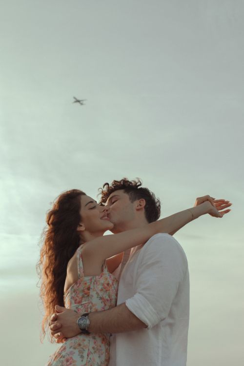 A girl and a boy embracing in a hug while he kisses her on the cheek.