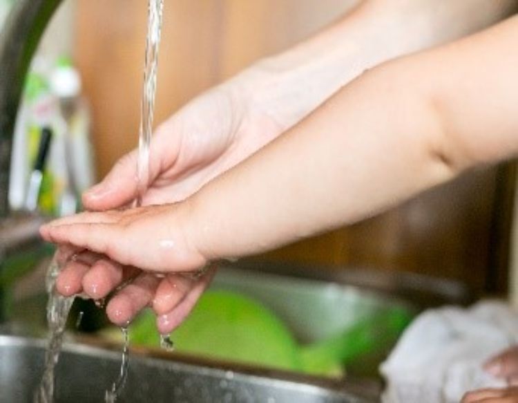 A child washing their hands at a sink.