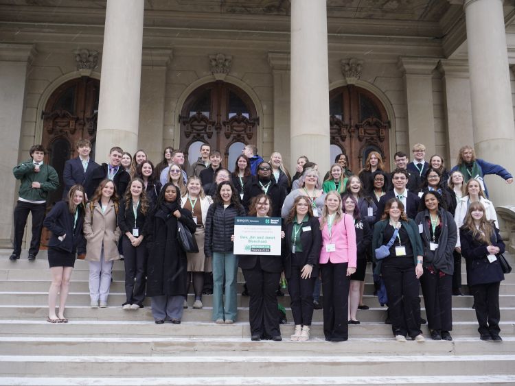 A group of youth on the Michigan State Capitol steps holding a sign that says 