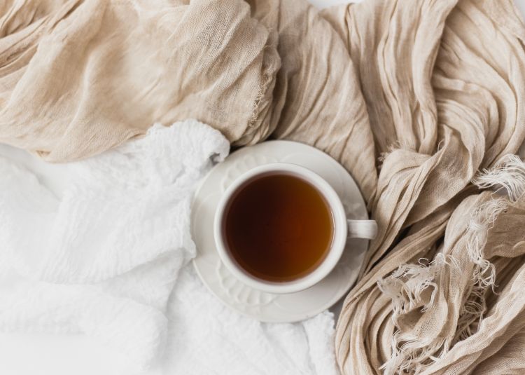 Tea in a mug on a bed.