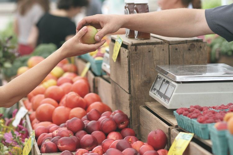 Person purchasing an apple at a market.