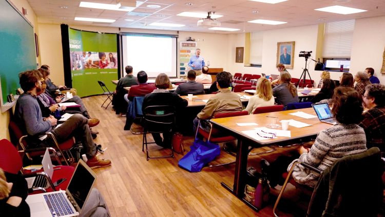 People gather in a room to listen to a presentation.