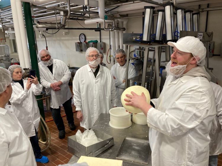 person holds a wheel of cheese to show to participants