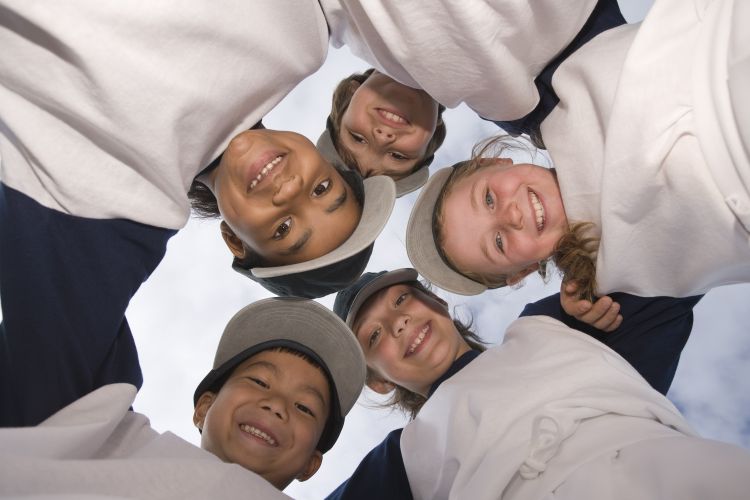 Five kids with their arms around each other in a huddle.