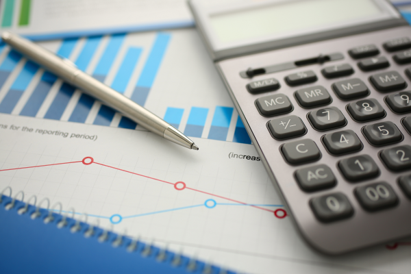 Silver calculator and financial statistics on clipboard pad at office table closeup.