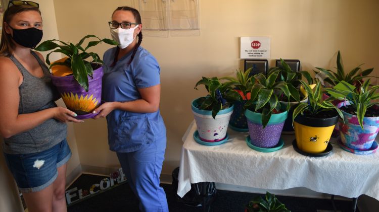 Two women pose with decorated potted plants