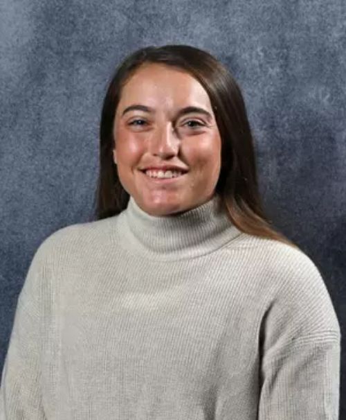 A dark haired woman with a pale sweater on.