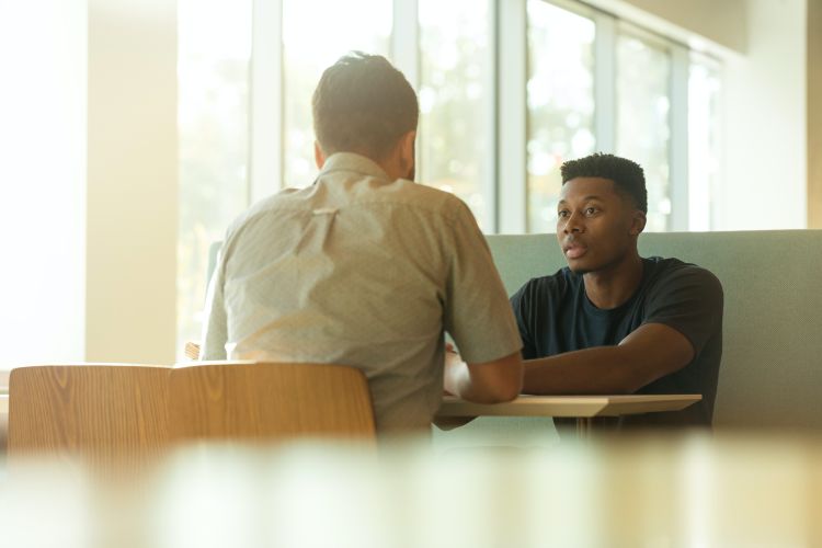 Two people sitting at a table while talking to each other.